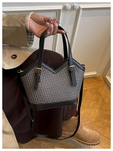 Detail of woven houndstooth pattern tote bag with leather trim and gold buckles
