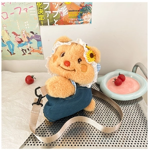 Detailed view of ginger plush bear bag with lace hat and blue denim overalls