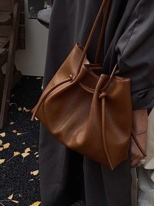 Retro-Eimerbeutel aus Leder in Karamell mit Kordelzug und Knotendetails am Model gezeigt