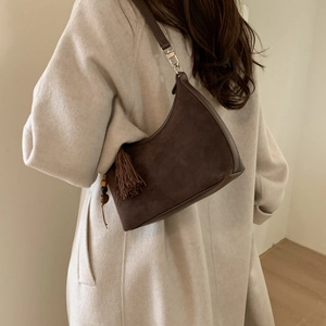 Detail of dark brown suede crescent bag featuring retro tassel and wood bead accents