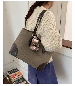 Dettaglio della grande borsa tote leopardata con finiture in pelle marrone e charm