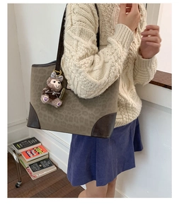 Dettaglio della borsa tote leopardata con angoli in pelle e un ciondolo a forma di orso