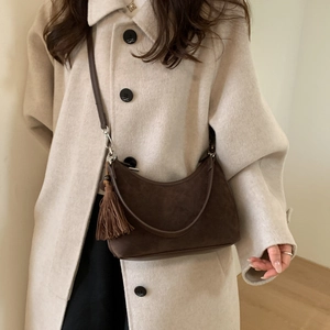 Detail of dark brown suede crescent bag with side tassel and long leather strap