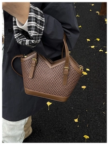 Detailed view of woven leather handbag featuring retro trapezoid design and gold hardware