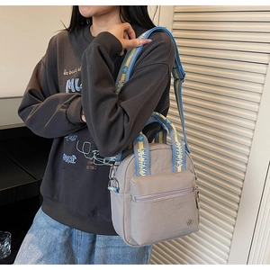 Détail du sac à bandoulière en nylon gris clair avec sangles bleu et jaune