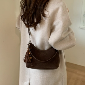 Detail of dark brown suede shoulder bag with long leather tassel and wooden bead