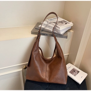Detailed view of caramel brown faux leather tote with visible grain and middle seam stitching