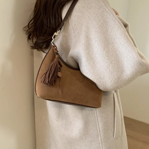 Close-up of brown suede moon bag featuring decorative fringe and metallic silver hardware
