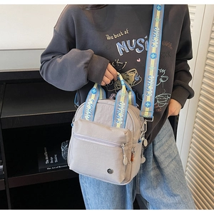 Détail du sac bandoulière en nylon gris avec sangle à motifs porté par un mannequin