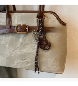 Detail der Vintage-Tragetasche mit Metallschnalle, braunem Griff und Abakus-Anhänger