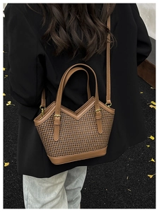 Close-up of brown woven tote bag with V-shaped top and golden metal hardware details