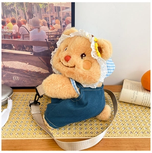 Detail of plush bear crossbody bag in blue denim overalls and a lace floral hat