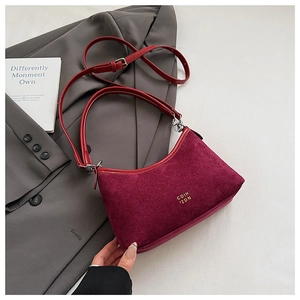 Detail der weinroten Wildleder-Schultertasche mit Goldlogo und verstellbarem Lederriemen