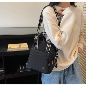 Détail du sac à bandoulière en nylon noir avec large sangle jacquard à motifs floraux