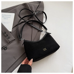 Detail einer schwarzen Wildleder-Hobo-Tasche mit verstellbarem Gurt und Blazer