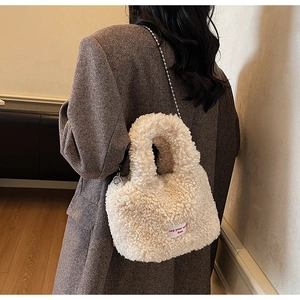 Vista posteriore di una modella con borsa a secchiello in peluche color crema e catena