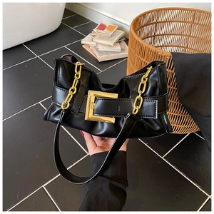 Detail showing soft black pleated leather texture and large gold buckle of the shoulder bag