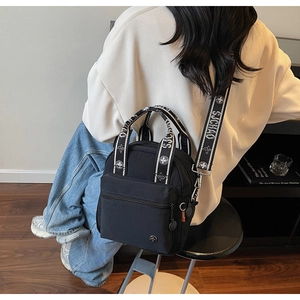 Détail du sac bandoulière en nylon noir avec une large sangle imprimée et un style moderne