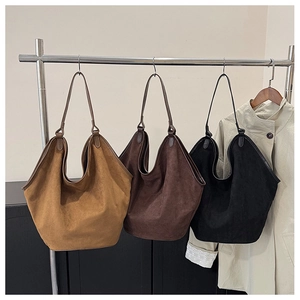 Three suede tote bags in khaki, brown, and black hanging on a display rack for close-up view