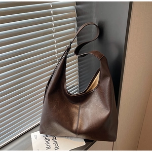 Detail view of large dark brown leather hobo bag with pebble texture and vertical stitching