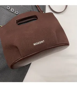 Detail view of dark brown mixed leather bucket bag with silver MOEDNT brand logo text