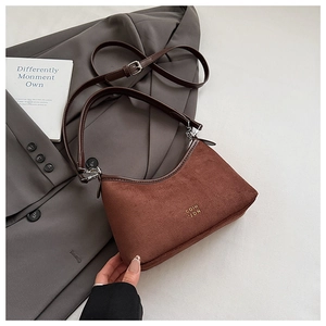 Details einer dunkelbraunen Wildleder-Hobo-Tasche mit Lederriemen und goldenem Logo
