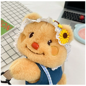 Detail of cute yellow plush bear backpack with lace hat and blue overalls