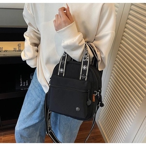 Détail du sac bandoulière en nylon noir avec sangle large imprimée et poche avant zippée