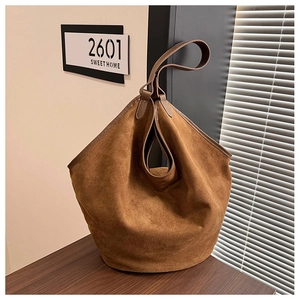 Close-up of deep brown suede bucket bag texture and folded design on wooden table