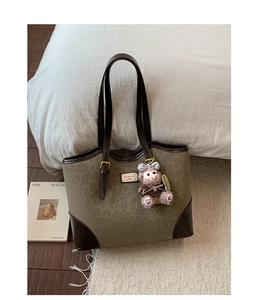 Dettaglio della borsa tote retrò leopardata con finiture in pelle e ciondolo peluche