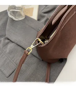 Detail of high-quality gold metal hardware and smooth zipper on brown suede bucket bag