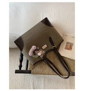 Dettaglio della borsa tote vintage leopardata con manici in pelle marrone e ciondolo orso