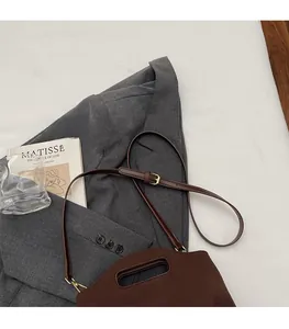 Close-up of brown bucket bag showing adjustable shoulder strap and metal hardware detail