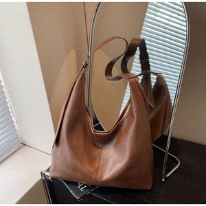 Detailed close-up of brown PU leather shoulder bag with vertical stitching and soft texture
