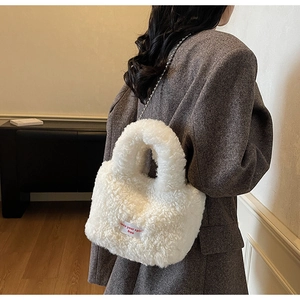Dettaglio della borsa a secchiello in peluche bianca con catena e etichetta tessuta