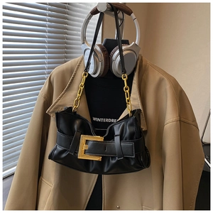 Detail of black crescent shoulder bag featuring large gold buckle and metal chain strap