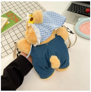 Detail of yellow plush bear bag with a blue denim overall and sunflower sun hat