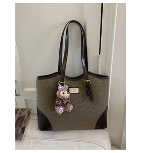 Dettaglio della borsa tote leopardata con manici in pelle e ciondolo a orsetto