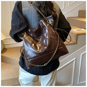 Detail shot of a dark brown quilted chain tote bag with glossy finish and metal strap
