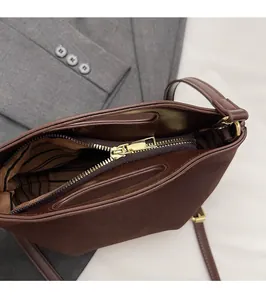 Detailed close-up of the smooth gold zipper and striped lining on a brown suede bag