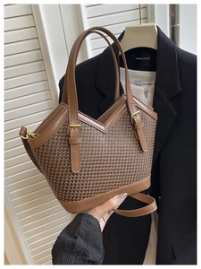 Detail of a brown woven tote bag with V-cut top and dual gold pin buckles for women
