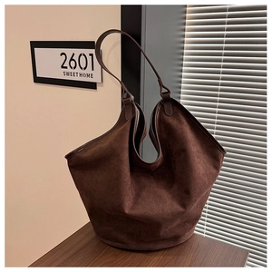 Detail of soft dark brown suede tote bag on a wooden table with home decor