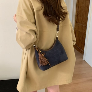 Detail of navy suede hobo bag with tassel and leather strap worn with khaki trench coat
