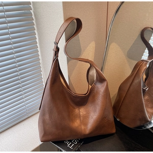 Detailed close-up of brown textured leather shoulder bag with adjustable strap and retro design
