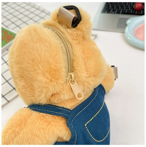 Detail shot of the plush bear backpack featuring a yellow fur texture and blue denim overalls