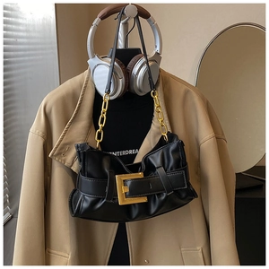 Detail of black pleated shoulder bag featuring a large gold buckle and thick chain strap