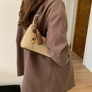 Detail of vintage beige shoulder bag with brown tassel and wooden bead accents