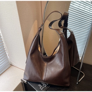 Detail of dark brown leather tote bag showing soft texture and contrast stitching