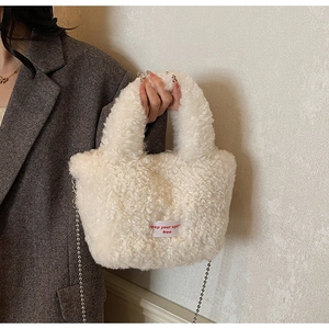 Dettaglio della borsa a secchiello in peluche bianca con catena d'argento e etichetta