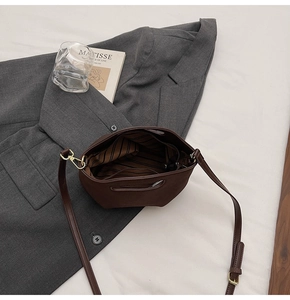 Detail view of the brown bucket bag showing the striped inner lining and zip pocket